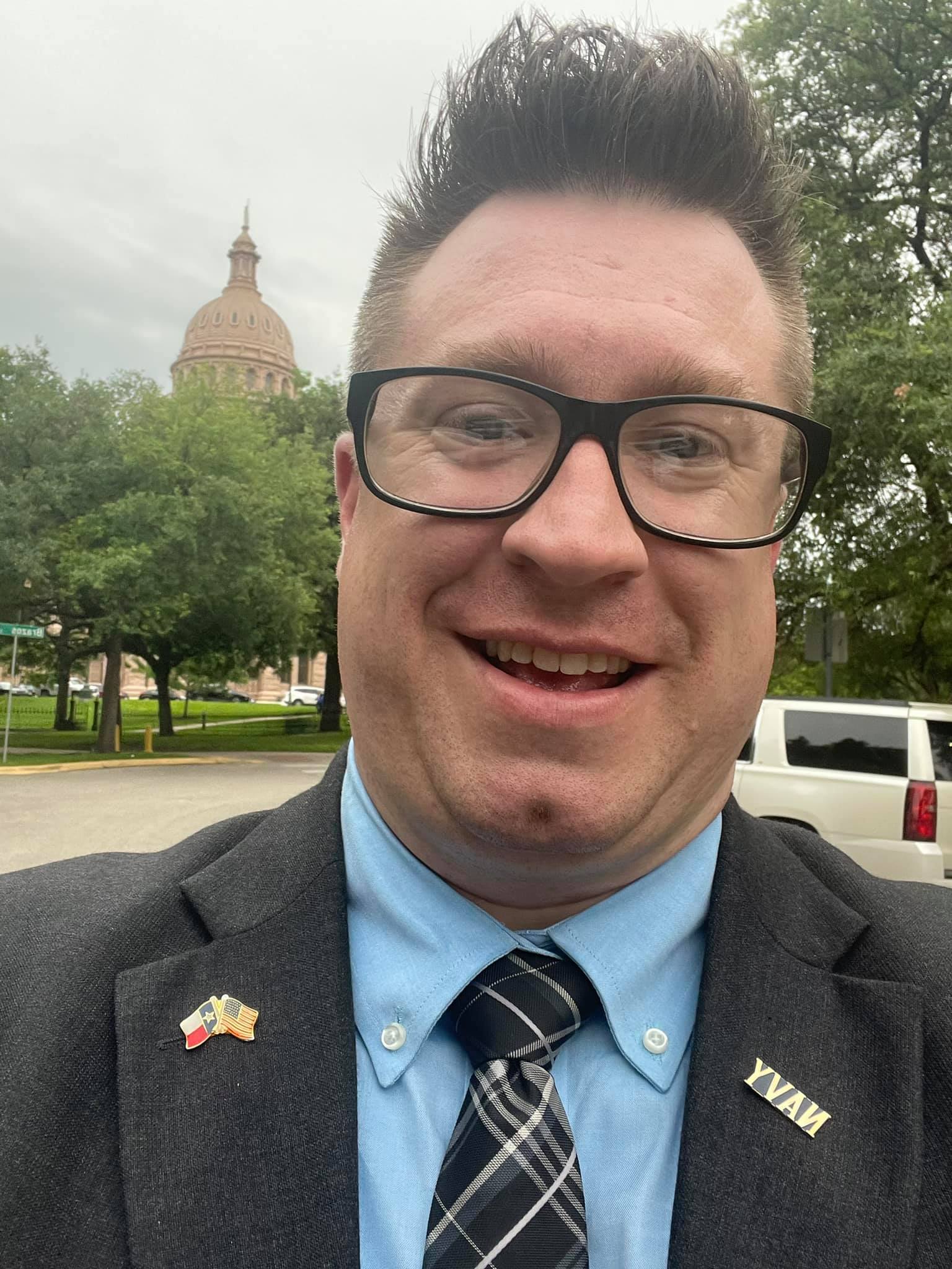 Jesse Williams standing in front of Texas capitol in a dress suit